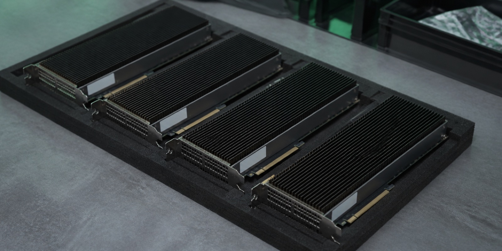 Several large AI accelerator cards with heavy black heatsinks laid out on antistatic foam on a workbench, each with a blank asset label